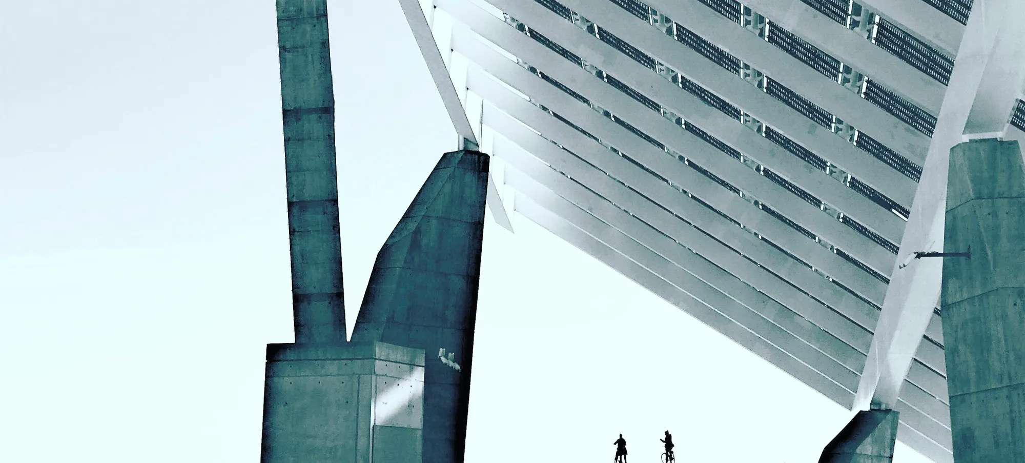 Two tiny people standing under a huge futuristic structure
